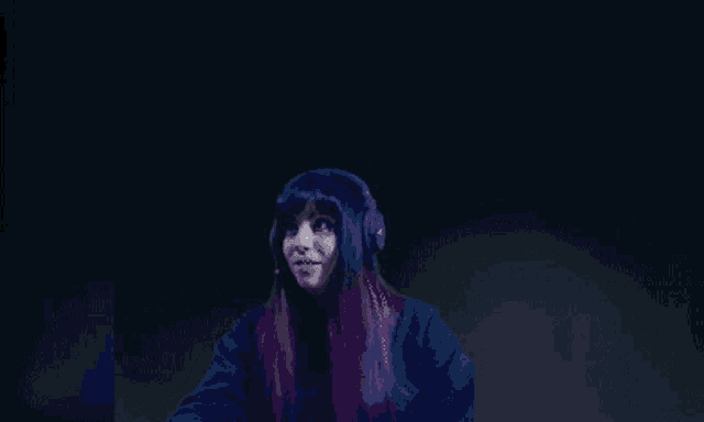 a woman with purple hair is wearing headphones and a black shirt