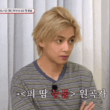 a young man with blonde hair is wearing a striped shirt