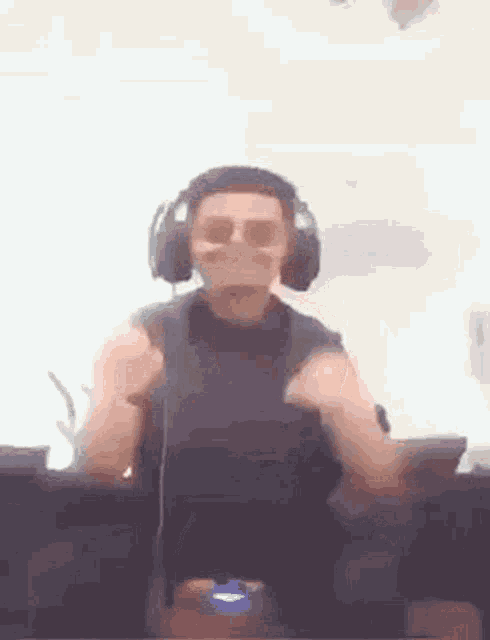 a man wearing headphones and sunglasses is dancing in front of a computer screen .