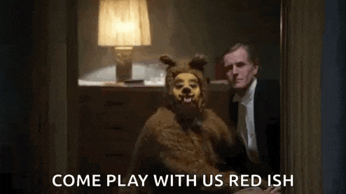 a man in a suit and tie is standing next to a teddy bear in a room .