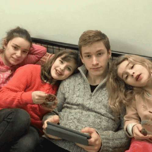 a group of children are posing for a picture while one of them is holding a tablet