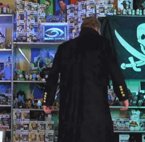 a man in a black coat stands in front of a blind wave display