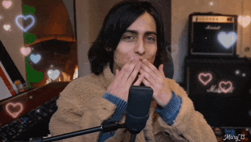 a man blowing a kiss in front of a microphone with hearts behind him