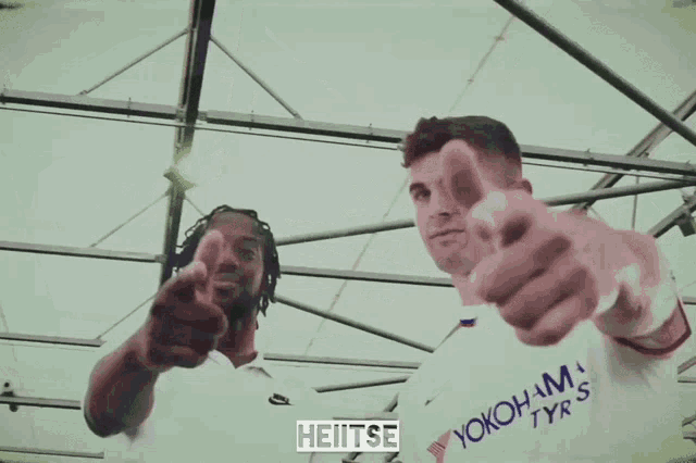 two men are giving a thumbs up and one has a shirt that says yokohama on it