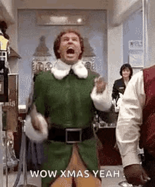 a man in a green elf costume is dancing in a room with other people .