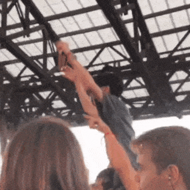 a group of people are standing under a roof with their arms up
