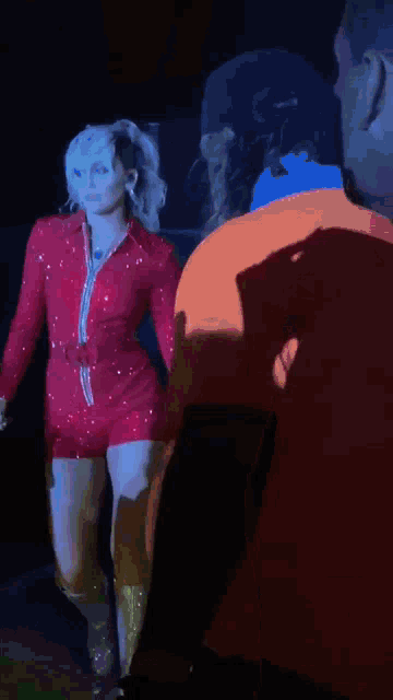 a woman in a red jumpsuit and boots stands on a stage