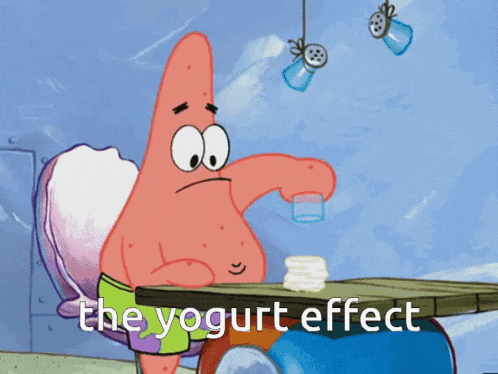 patrick star from spongebob squarepants is sitting at a table with a glass of yogurt in his hand