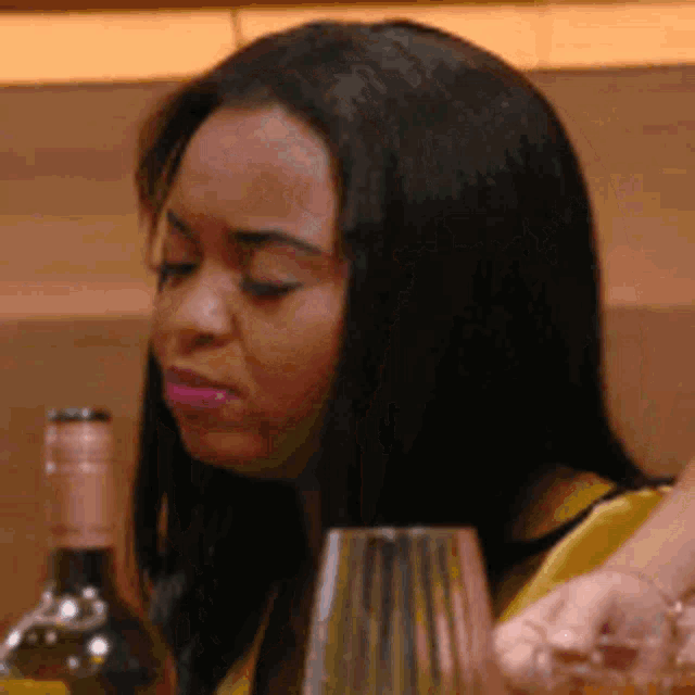 a woman sitting at a table with a bottle of wine and a glass .