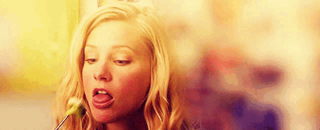 a woman is sticking her tongue out while eating a vegetable .