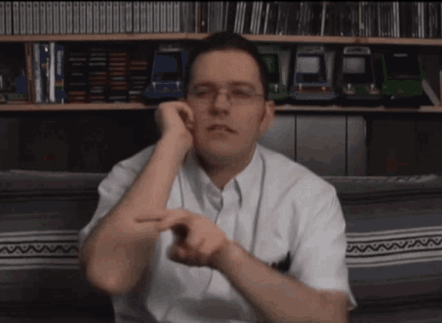 a man with glasses and a white shirt is sitting on a couch