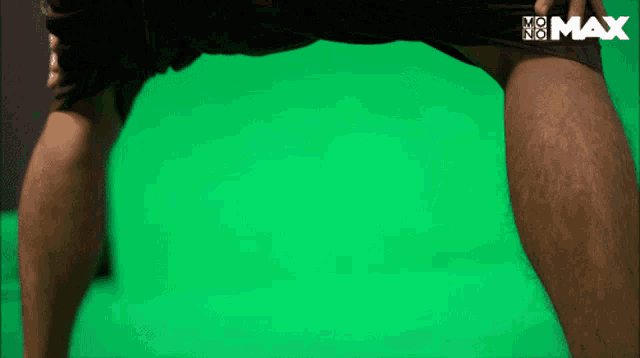 a person 's legs are shown in front of a green screen that says no max on it