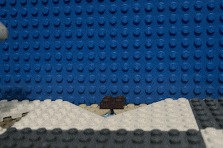 a lego dinosaur is standing in front of a blue lego wall