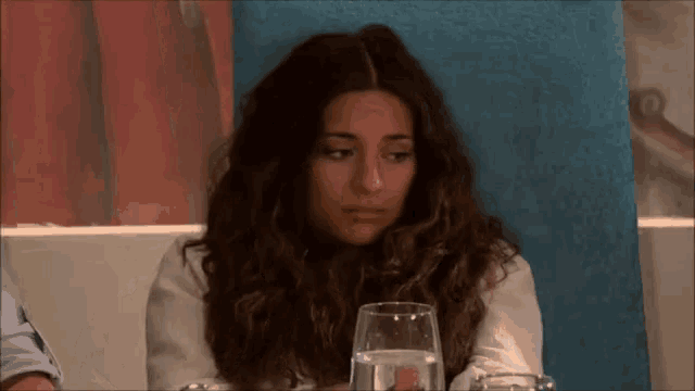 a woman is sitting at a table with a glass of water