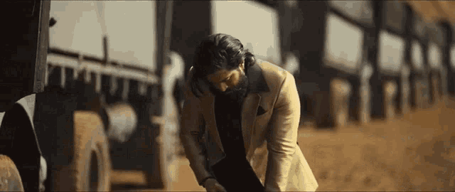 a man in a suit and beard is kneeling down in the dirt .
