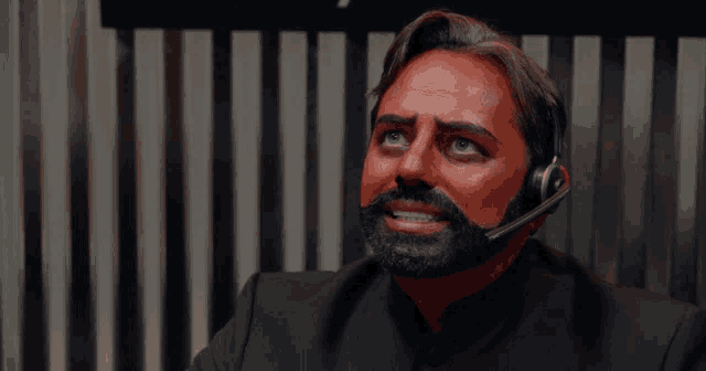a man with a red face and a beard wearing a headset