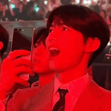 a man in a suit and tie is taking a picture of himself with his phone .