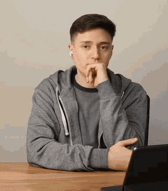 a young man wearing ear buds sits at a desk