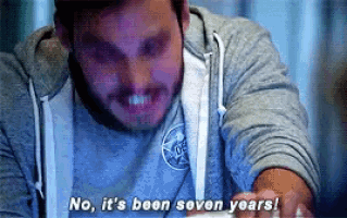 a man in a gray hoodie is sitting at a table and says no , it 's been seven years .