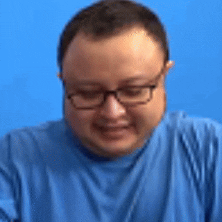a man wearing glasses and a blue shirt is making a face .