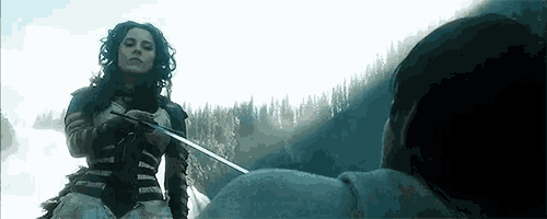 a woman is holding a sword in front of a man in a field .