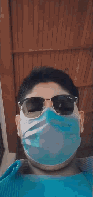 a young man wearing a face mask and sunglasses .