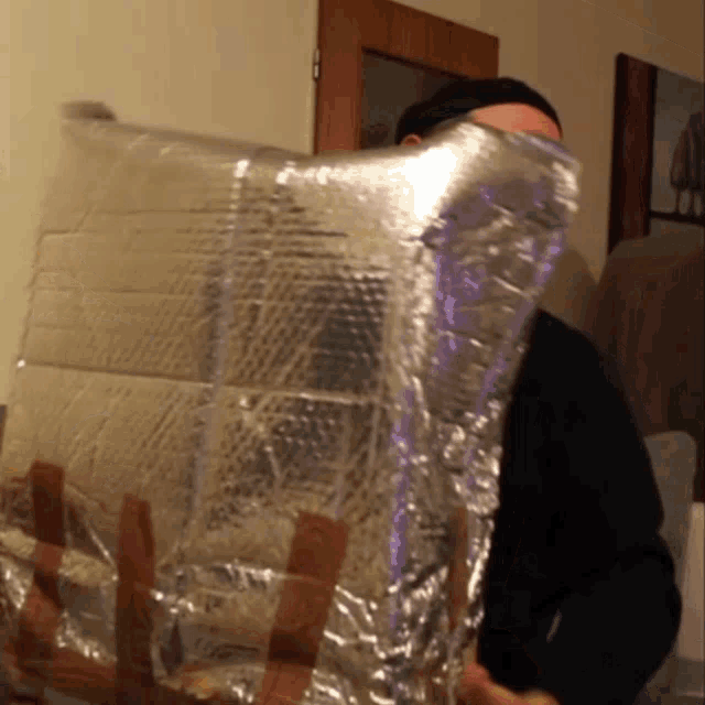 a man is holding a piece of aluminum foil over his face