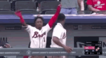 a baseball player wearing a braves jersey is raising his arms in the air