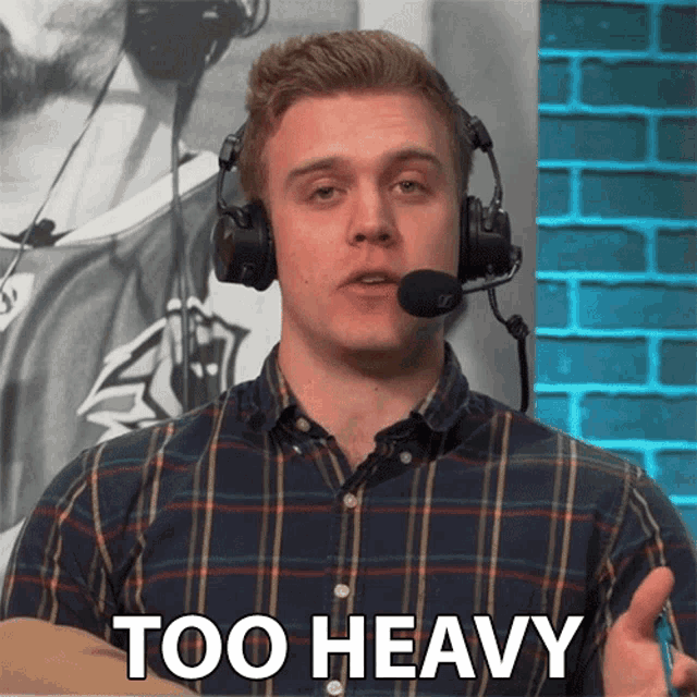a man wearing headphones says " too heavy " in front of a brick wall