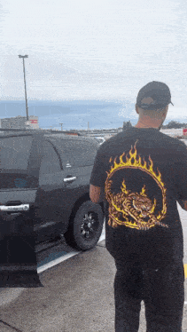 a man wearing a black shirt with a tiger and flames on the back