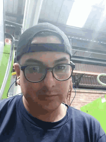 a man wearing glasses and a hat is looking down at the camera