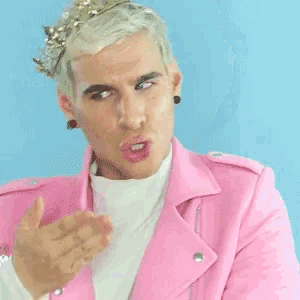 a man wearing a pink jacket and a crown on his head makes a funny face