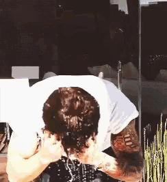 a man with a tattoo on his arm is washing his face with water