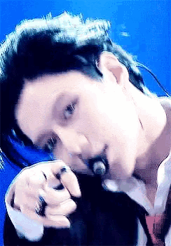 a close up of a person singing into a microphone with a blue background