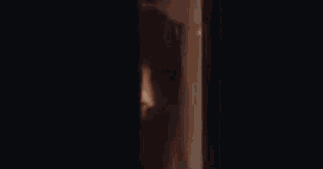a close up of a woman 's face peeking out from behind a door .