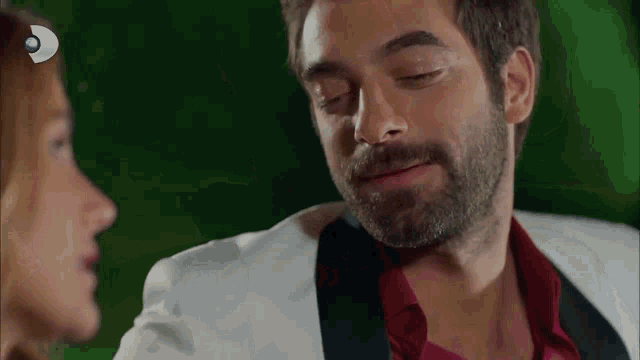 a man with a beard and a red shirt is looking at a woman .