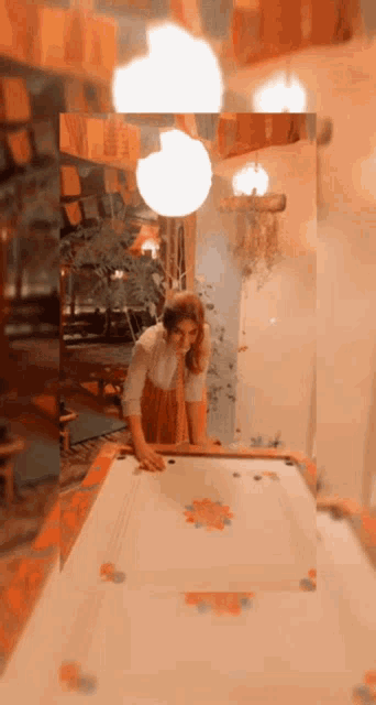 a woman is playing a game of carrom in a room with flags on the ceiling