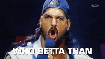 a man in a blue hat is screaming into a microphone and the words who betta than are visible in the background