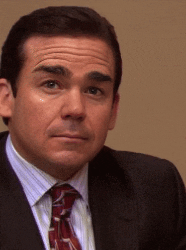 a man wearing a suit and tie is looking at the camera .