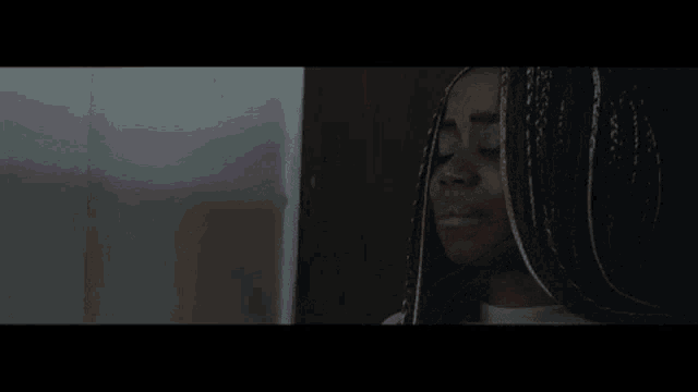 a woman with braids is covering her mouth with her hand