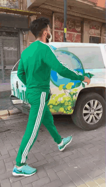 a man wearing a mask is walking in front of a white truck with a painting of flowers on it