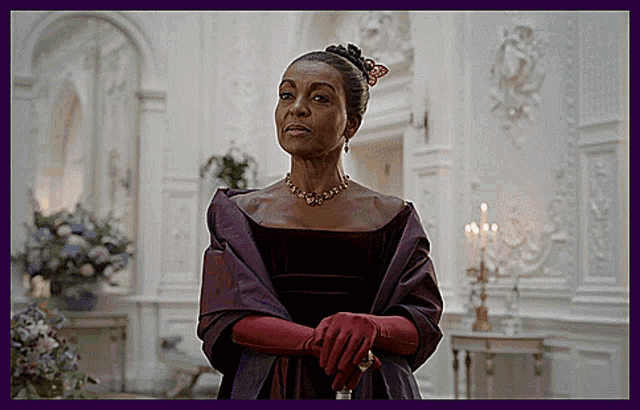 a woman in a purple dress and red gloves is standing in a room