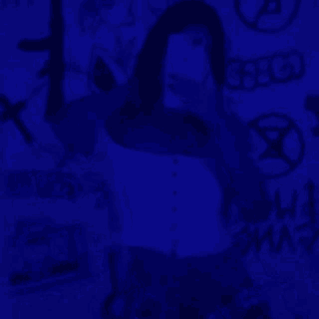 a woman is taking a selfie in front of a blue wall with graffiti .