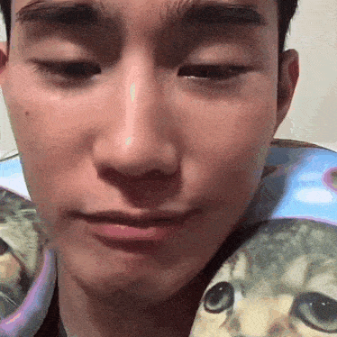 a close up of a man 's face with a cat on his shirt