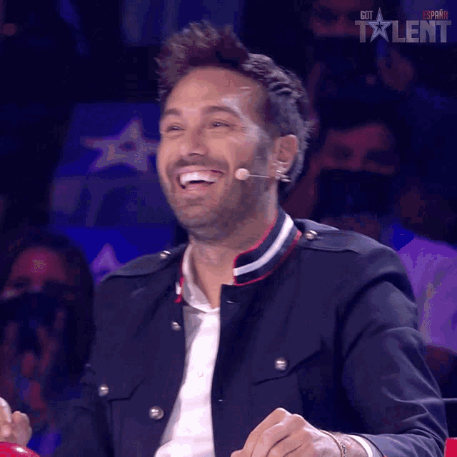 a man is laughing in front of a microphone that says got talent spain