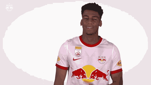 a soccer player wearing a red bull jersey is smiling