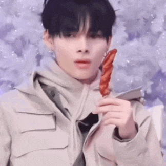 a young man is holding a piece of meat in his hand in front of a purple background .