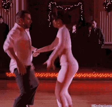 a man and a woman are dancing on a dance floor in a dark room .