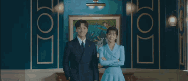 a man in a suit and tie is standing next to a woman in a blue dress in a room .