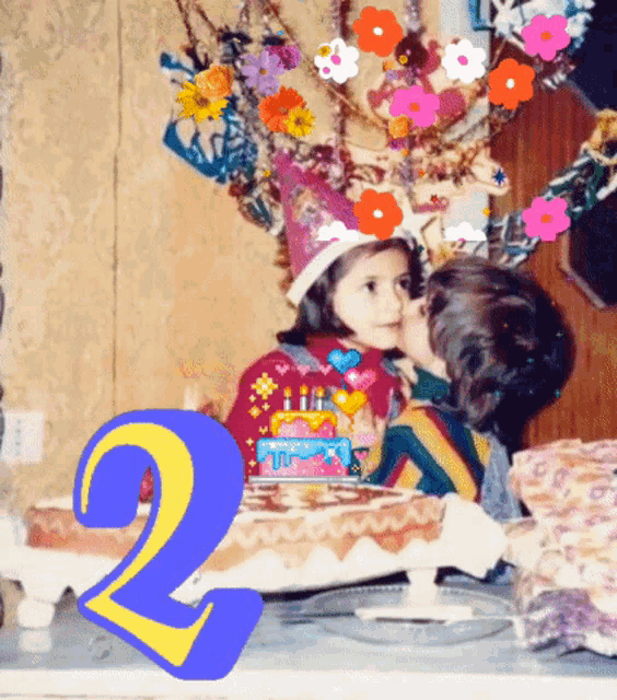 a little girl is kissing a boy on the cheek in front of a birthday cake with the number 2 on it